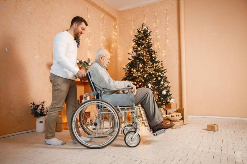 young-man-his-old-father-wheelchair-sitting-near-christmas-tree sasupportive